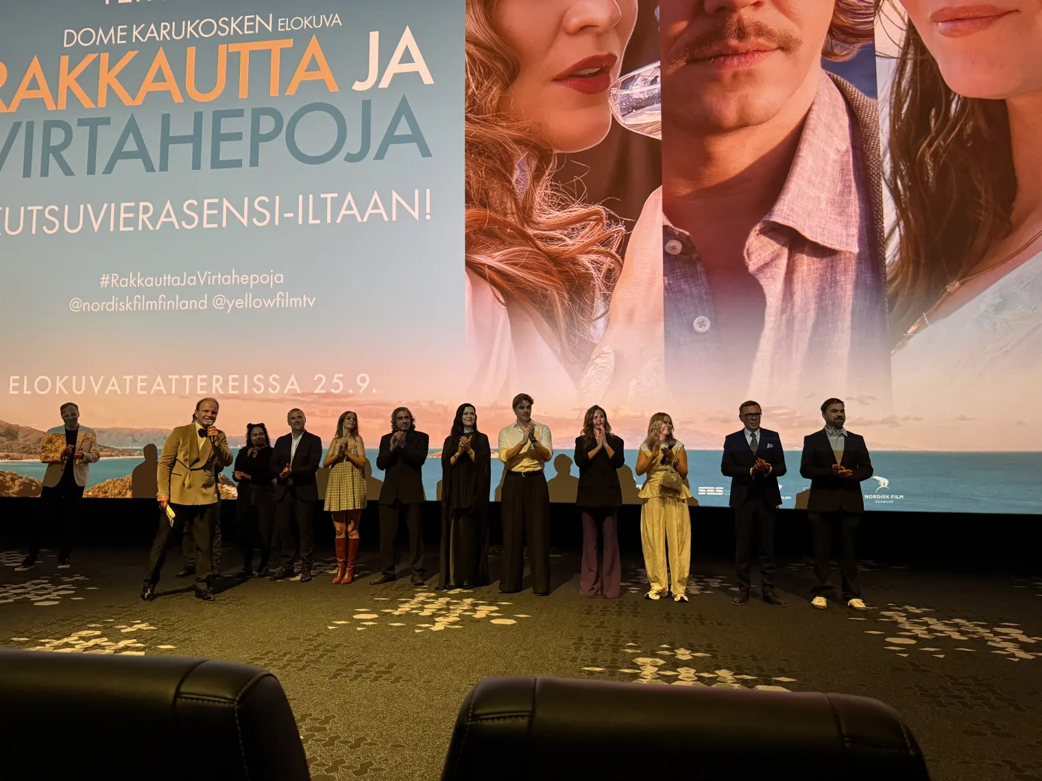 The cast and crew of Hippo Love on stage in front of the cinema screen, Dome Karukoski speaking into a microphone.